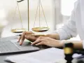 Mani che lavorano al computer, con bilancia della giustizia e martelletto. Uno smart worker legale.