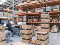 Magazzino pieno di scatoloni SHAD, pronti per spedizioni in un volatile ecommerce. Un lavoratore sistema la merce.