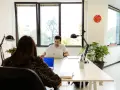 Uomini e donne lavorano in un ufficio moderno, un esempio di coworking. Il significato di coworking è condivisione di spazi e idee.