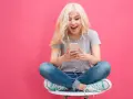 Ragazza bionda con cuffie ascolta musica sul suo smartphone, un esempio di come il mobile marketing cattura l'attenzione.