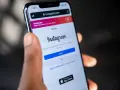 Mano che tiene uno smartphone con la pagina di accesso di Instagram aperta. Forse qualcuno sta pensando cosa vuol dire droppare un post.