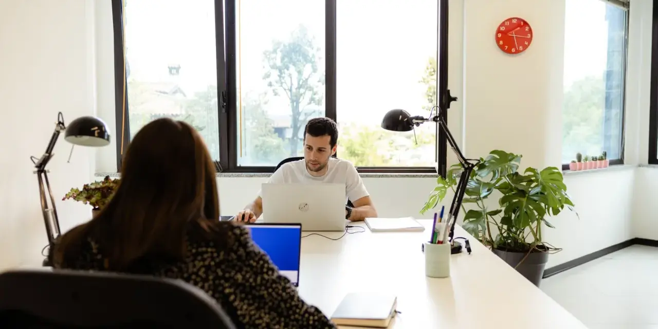 Uomini e donne lavorano in un ufficio moderno, un esempio di coworking. Il significato di coworking è condivisione di spazi e idee.