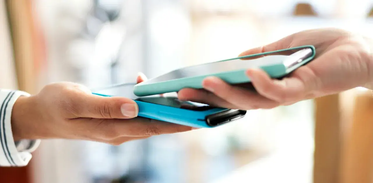Due mani avvicinano due smartphone per un tap, forse per un pagamento o per scambiare dati.