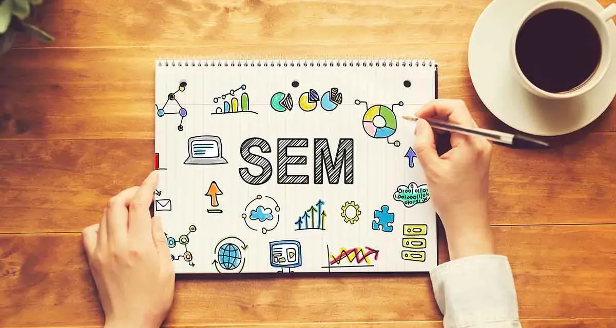 Mani scrivono "SEM" su un quaderno, circondato da icone di grafici, dati e tecnologia. Capire il SEM è fondamentale per il successo online.