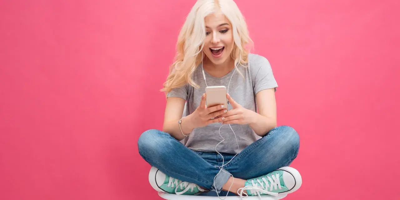 Ragazza bionda con cuffie ascolta musica sul suo smartphone, un esempio di come il mobile marketing cattura l'attenzione.