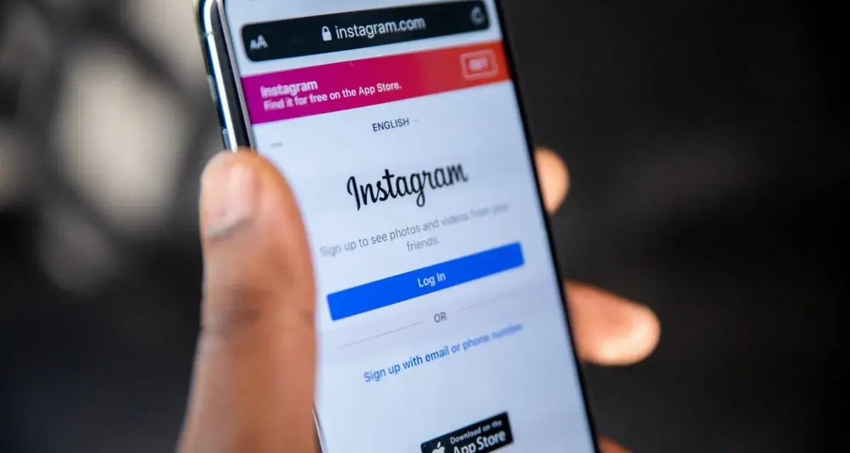 Mano che tiene uno smartphone con la pagina di accesso di Instagram aperta. Forse qualcuno sta pensando cosa vuol dire droppare un post.