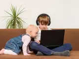 Bambini curiosi, forse la generazione dei 2012, esplorano un laptop. Uno con cuffie, l'altro gattona.