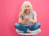 Ragazza bionda con cuffie ascolta musica sul suo smartphone, un esempio di come il mobile marketing cattura l'attenzione.
