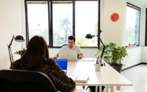 Uomini e donne lavorano in un ufficio moderno, un esempio di coworking. Il significato di coworking è condivisione di spazi e idee.