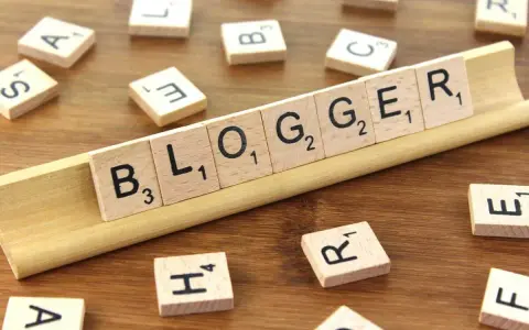 Le tessere del gioco compongono la parola "BLOGGER", definendo il significato di chi condivide pensieri e esperienze online.