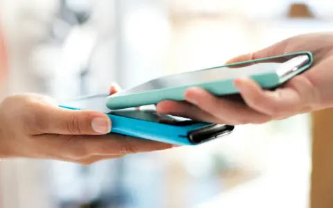 Due mani avvicinano due smartphone per un tap, forse per un pagamento o per scambiare dati.