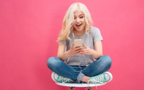 Ragazza bionda con cuffie ascolta musica sul suo smartphone, un esempio di come il mobile marketing cattura l'attenzione.