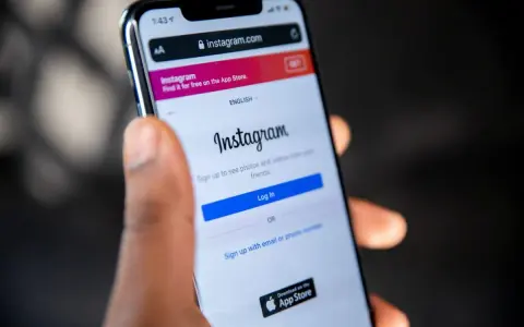Mano che tiene uno smartphone con la pagina di accesso di Instagram aperta. Forse qualcuno sta pensando cosa vuol dire droppare un post.
