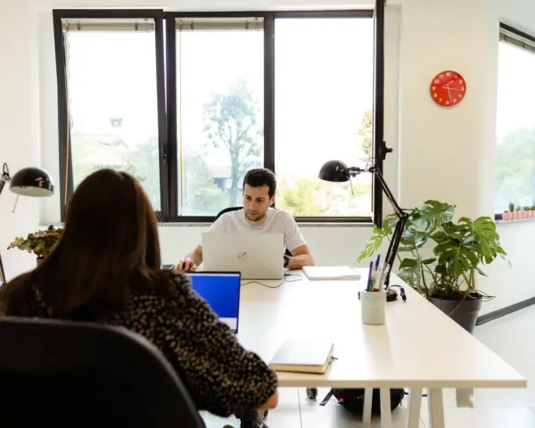Uomini e donne lavorano in un ufficio moderno, un esempio di coworking. Il significato di coworking è condivisione di spazi e idee.