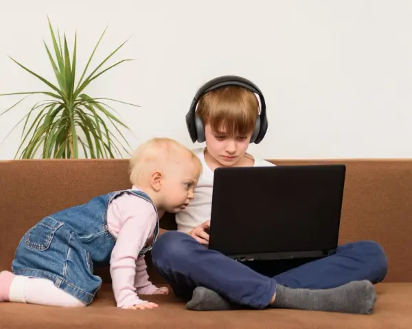Bambini curiosi, forse la generazione dei 2012, esplorano un laptop. Uno con cuffie, l'altro gattona.