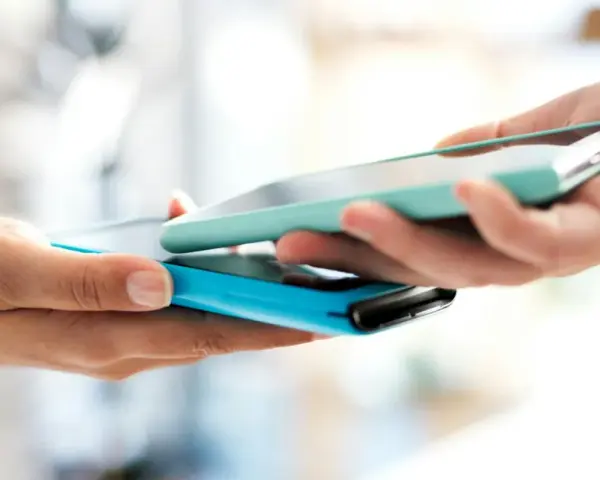 Due mani avvicinano due smartphone per un tap, forse per un pagamento o per scambiare dati.