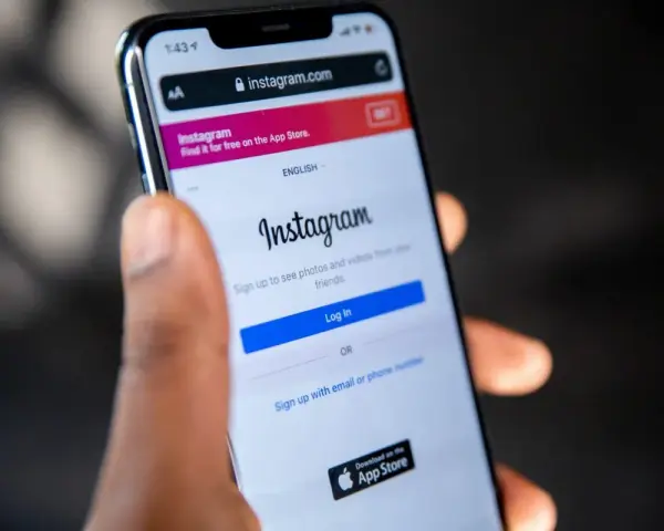 Mano che tiene uno smartphone con la pagina di accesso di Instagram aperta. Forse qualcuno sta pensando cosa vuol dire droppare un post.