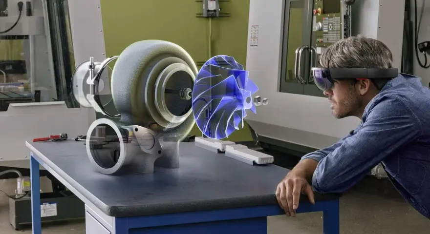 Un uomo con visore AR studia un ologramma di un turbocompressore, esplorando il suo significato tecnologico in officina.