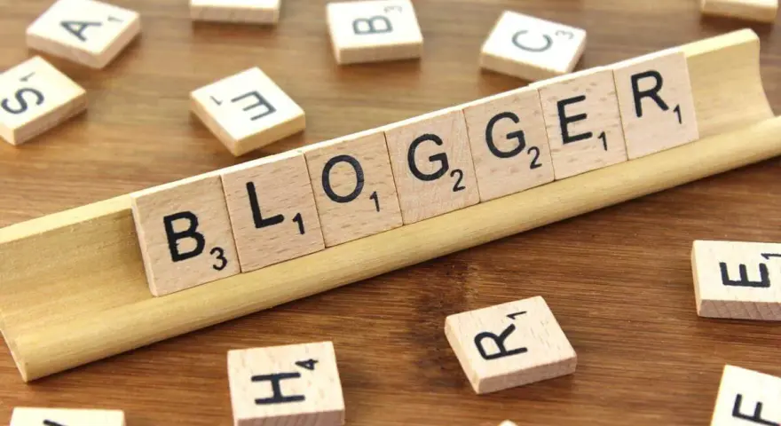 Le tessere del gioco compongono la parola "BLOGGER", definendo il significato di chi condivide pensieri e esperienze online.