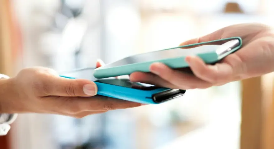 Due mani avvicinano due smartphone per un tap, forse per un pagamento o per scambiare dati.