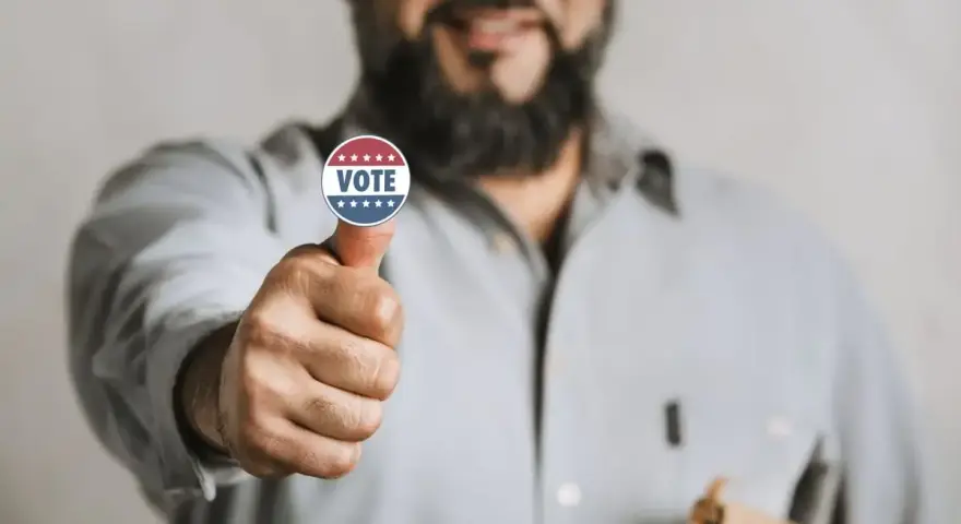 Uomo con adesivo "VOTE" sul pollice, un gesto di approvazione che simboleggia l'endorsement significato politico.
