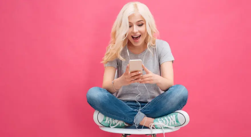 Ragazza bionda con cuffie ascolta musica sul suo smartphone, un esempio di come il mobile marketing cattura l'attenzione.