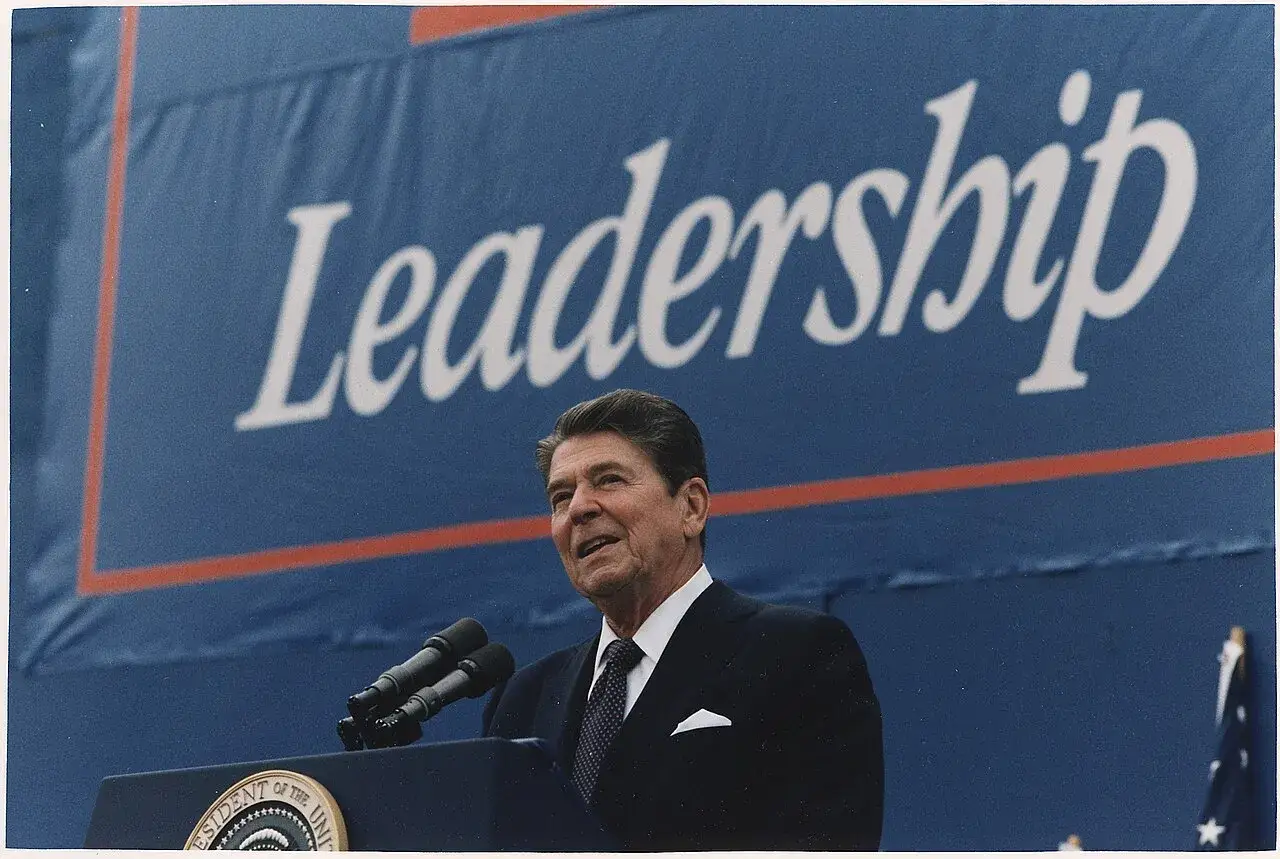 Ronald Reagan parla sotto uno striscione con la parola 