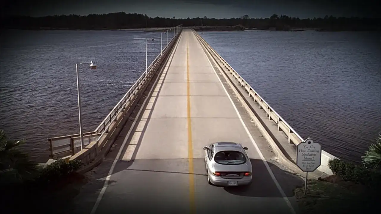 Un'auto attraversa un ponte solitario, un'immagine che evoca le riflessioni su 