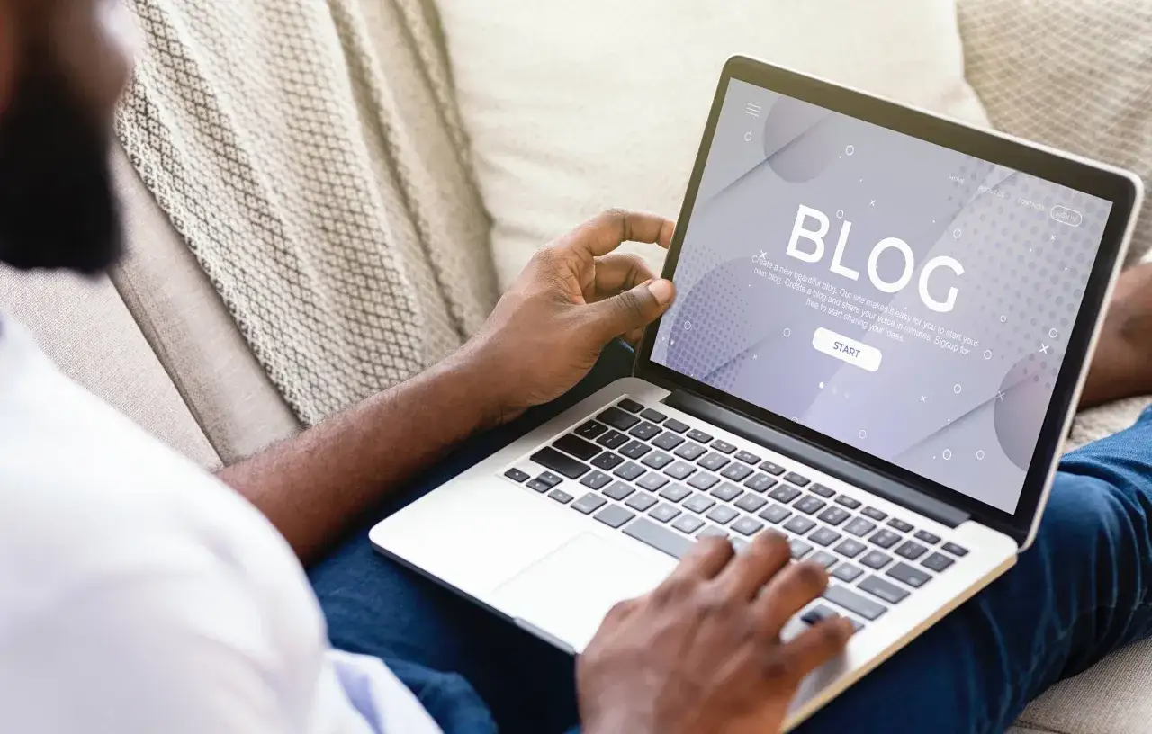 Uomo su divano usa laptop per creare un blog. Il significato di blogger &egrave; condividere idee online.