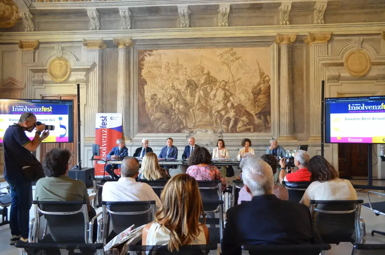Panel di relatori a Insolvenzfest, un evento dedicato a capire il pr significato delle crisi debitorie. Fotografo documenta la conferenza.