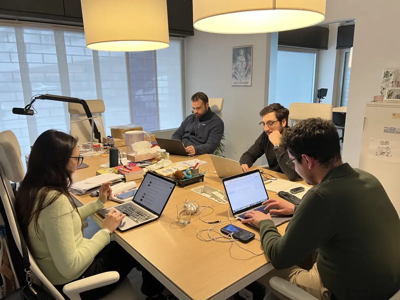Un team lavora in un ufficio moderno, concentrato sui propri laptop. Il significato di giornalista emerge dalla loro dedizione alla ricerca e alla comunicazione.