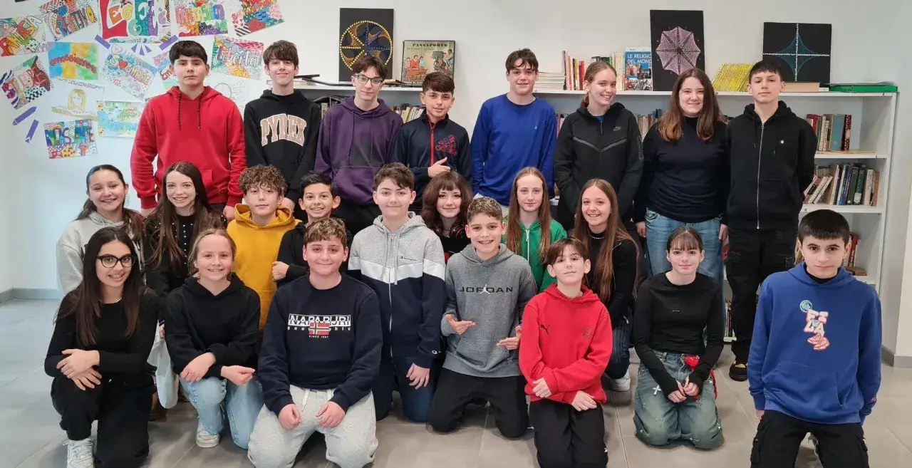 Un gruppo di ragazzi e ragazze, la generazione Z, posa sorridente in un'aula.
