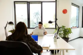 Uomini e donne lavorano in un ufficio moderno, un esempio di coworking. Il significato di coworking è condivisione di spazi e idee.